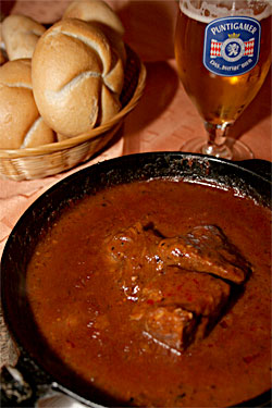 Gulasch mit Semmel und einem Glas Bier